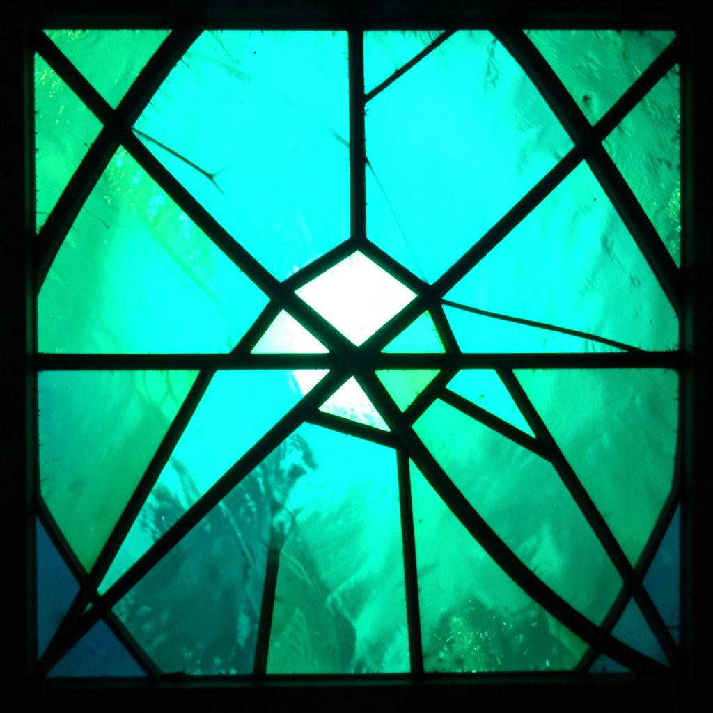 Stained-glass style illustration of a laptop screen with bold leaded segments in teal and amber tones, evoking a calm technical mood